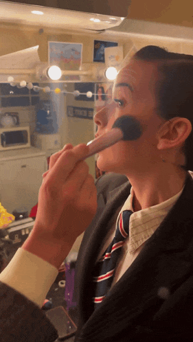 a man is applying makeup to another man 's face