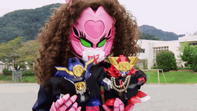 a girl with curly hair wearing a pink mask and holding a robot