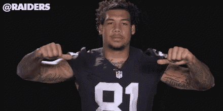 a man wearing a raiders jersey is flexing his muscles .