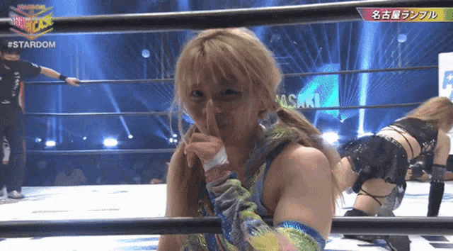 a woman in a wrestling ring holds her finger to her lips