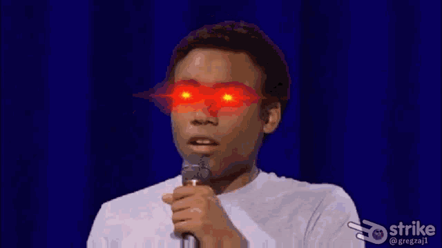 a man is holding a microphone with red eyes and the word good written on his face .