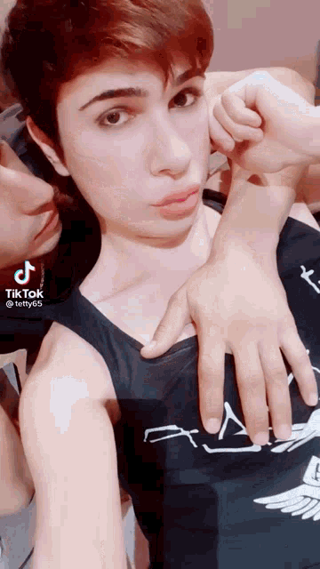 a man in a black tank top is making a funny face with his hands