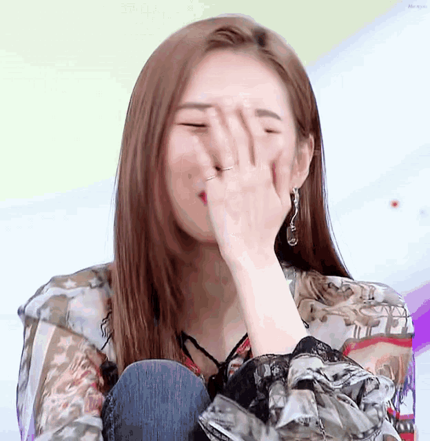 a young woman is covering her face with her hand .