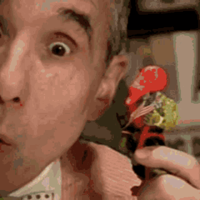 a man is holding a toy car in his hand and making a surprised face .
