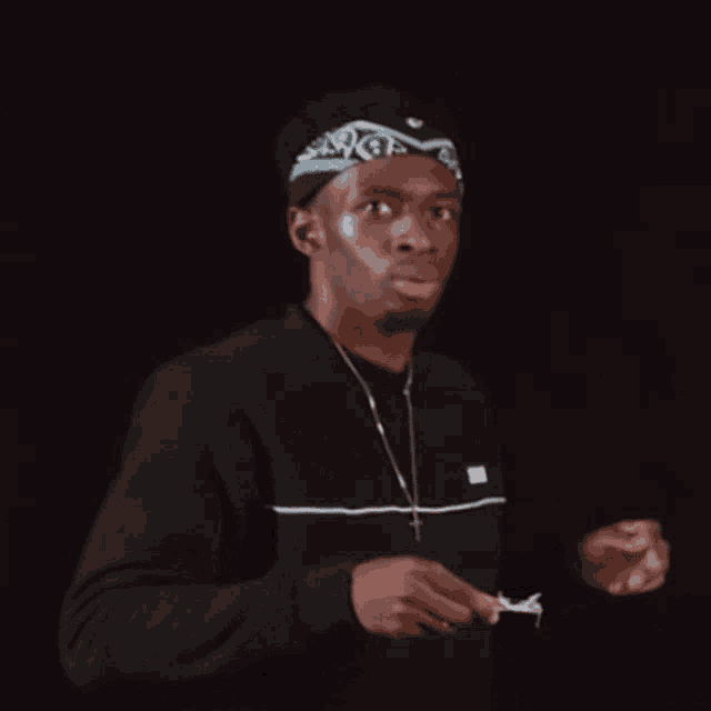 a man wearing a bandana and a necklace is holding a piece of paper .