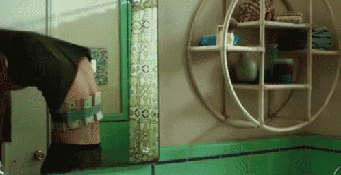 a bathroom with green tiles and a round shelf