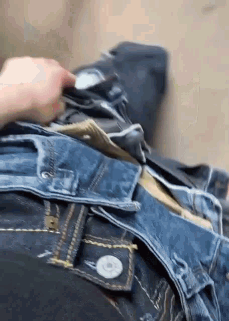 a person is holding a piece of paper in their pocket while wearing a pair of jeans .