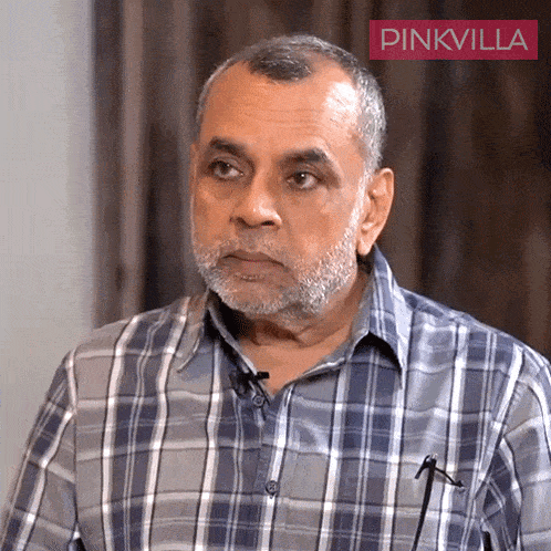 a man with a beard wearing a plaid shirt with a pinkvilla logo in the corner