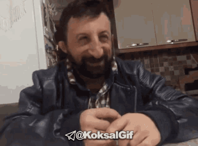 a man with a beard is sitting at a table with the hashtag @koksalgif on the bottom right