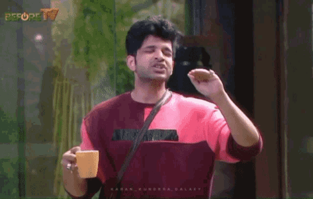 a man is holding a cup of coffee in front of a screen that says people tv