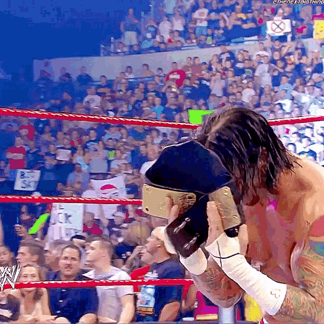 a man in a wrestling ring is holding a belt that says ' wwe ' on it