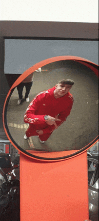 a man in a red adidas outfit is standing in front of a mirror