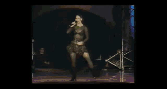 a woman in a black dress is singing into a microphone on a stage