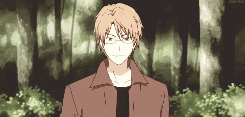 a man wearing glasses is standing in a forest .