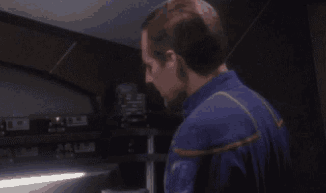 a man in a blue suit is standing in a dark room .