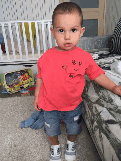 a young boy wearing a red shirt with a face on it