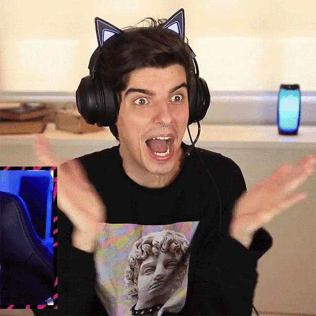 a man wearing headphones and a shirt with a statue on it is making a surprised face