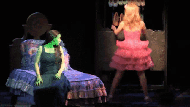 a woman in a green dress is sitting next to a woman in a pink dress