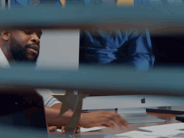 a man sits at a desk with an apple computer on it