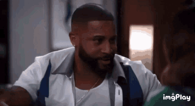 a man with a beard is wearing a white shirt and a blue and white jacket