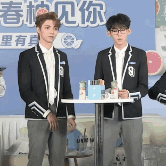 two young men standing next to each other in front of a sign in chinese