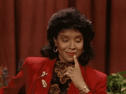 a woman in a red suit is making a funny face while holding her finger to her mouth .