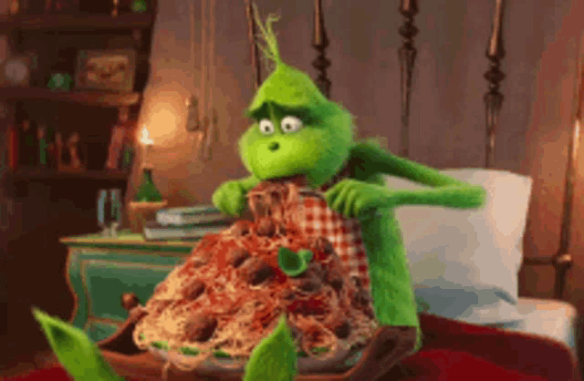 the grinch is sitting on a bed eating spaghetti and meatballs .
