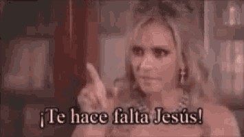 a woman is pointing at the camera and saying te hace falta jesus .