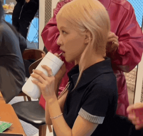 a woman with blonde hair drinking from a white cup