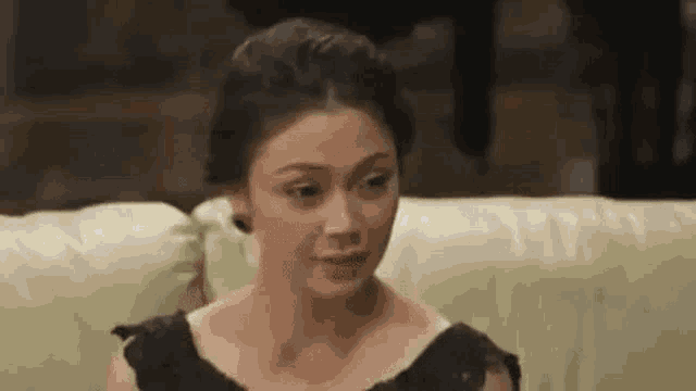 a woman is sitting on a couch and making a funny face .