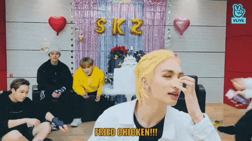 a group of boys are sitting in front of a sign that says fried chicken