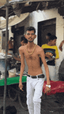 a shirtless man wearing white pants and a gold chain around his neck is standing in front of a cart