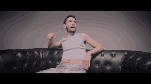a man in a purple tank top is sitting on a couch