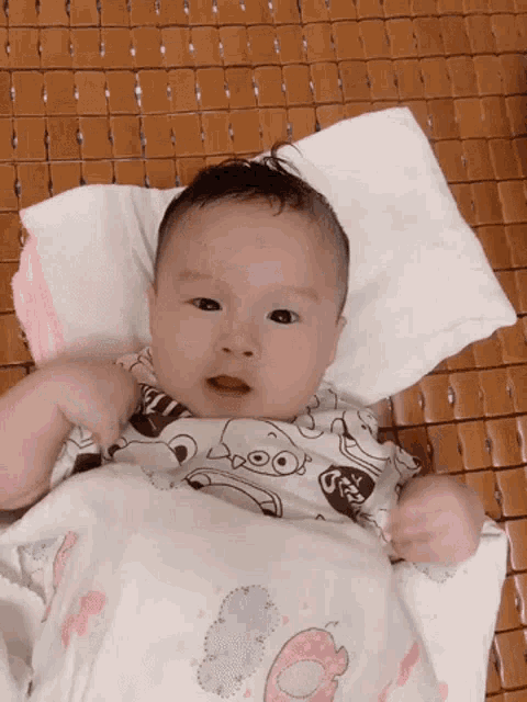 a baby is laying on a bed with a blanket that says ' donuts ' on it