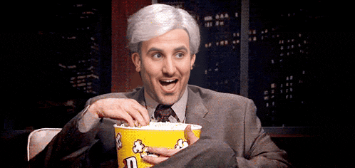 a man in a suit and tie is eating popcorn