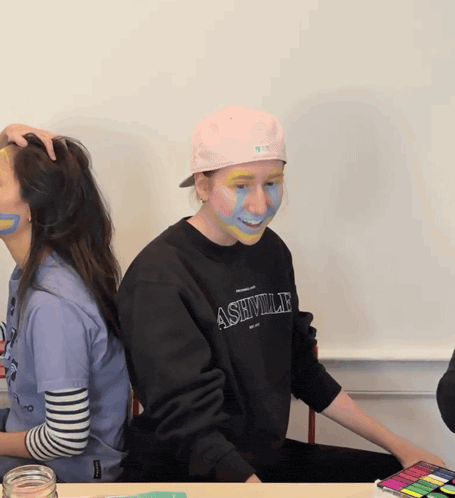 a person wearing an ashville sweatshirt has their face painted