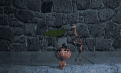 a cartoon ant is standing on a sidewalk next to a brick wall holding a leaf .