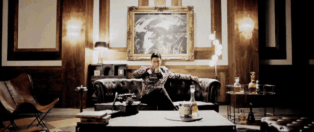 a man sits on a couch in a room with a painting on the wall