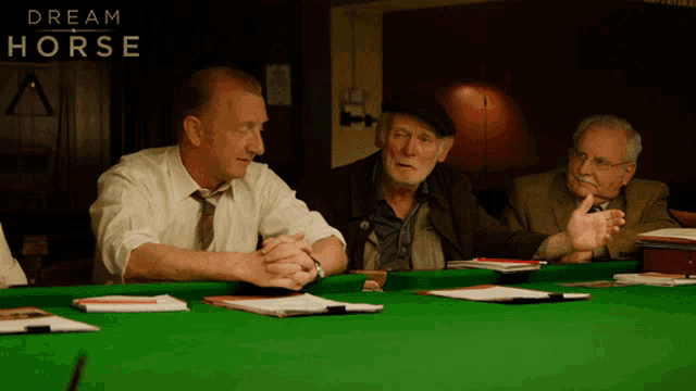 three men are sitting at a pool table with the words dream horse behind them