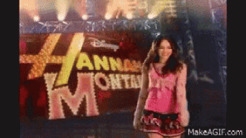 a girl in a pink shirt is standing in front of a sign that says hannah montana