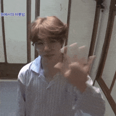 a young man wearing glasses and a striped shirt is waving