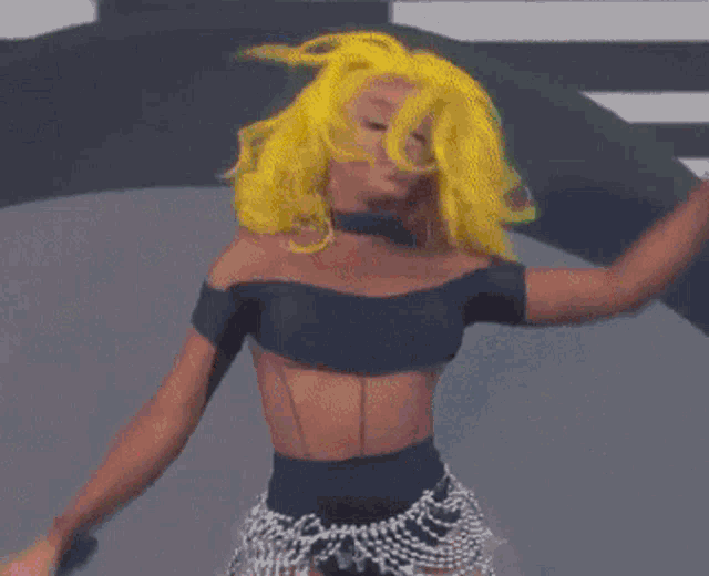 a woman with yellow hair is dancing in front of a colorful backdrop
