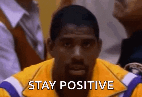 a man in a yellow jacket is saying `` stay positive '' while sitting on the bench .