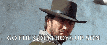 a man with a beard wearing a cowboy hat is standing in front of a wall .