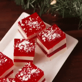 a white plate topped with red and white candy cane jelly squares .
