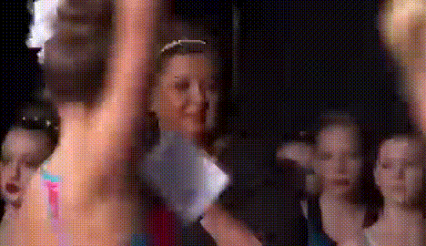 a group of young girls are dancing in front of a crowd of people .