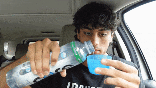 a man in a car is drinking from a bottle that says ccc on it