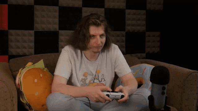 a man sitting on a couch holding a playstation controller