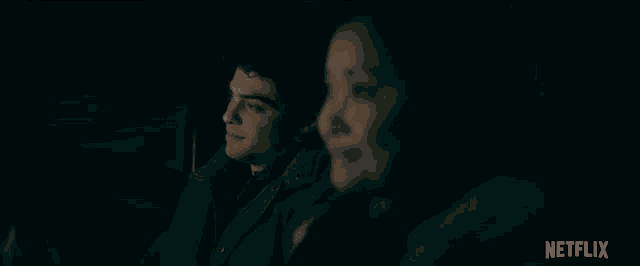 a man and a woman are sitting in the back of a car at night .