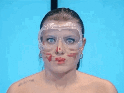 a woman wearing goggles and a tattoo on her shoulder has blood on her face .
